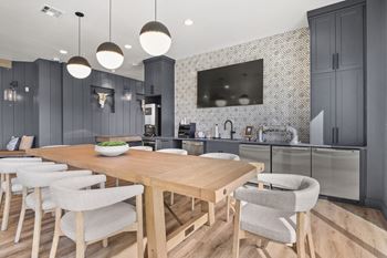 a dining area with a wooden table and chairs and a kitchen with gray cabinets at Parkside at Littleton Village, Colorado, 80122
