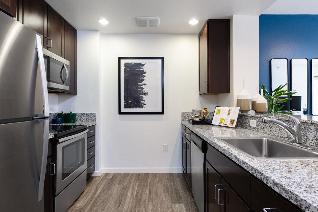 Mission Bay, San Francisco CA Apartments - STRATA at Mission Bay - Modern Kitchen with Hardwood-Style Flooring, Granite Countertops, Dark Wood Cabinetry, Stainless Steel Applainces, White Walls, and Framed Art