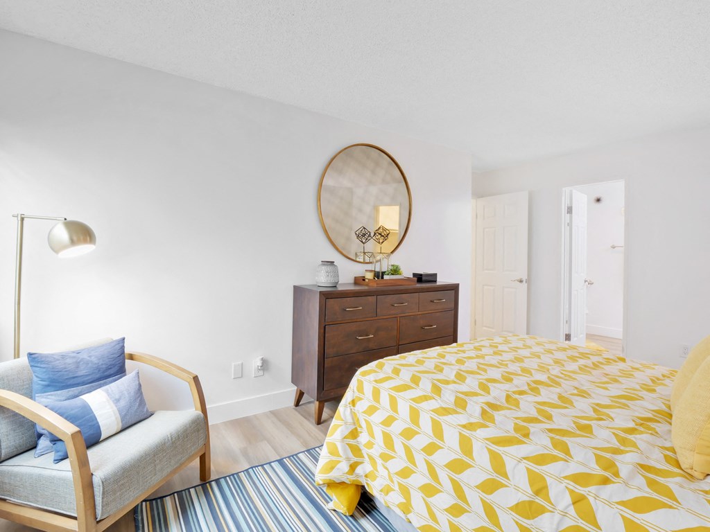 A bedroom with a bed, chair, and dresser at Verandas Apartments, West Covina, California