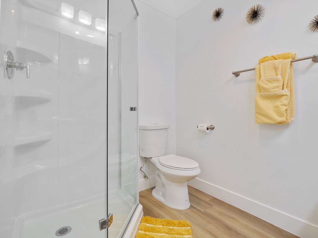 A white toilet sits in a bathroom next to a glass shower stall at Verandas Apartments, West Covina, 91791