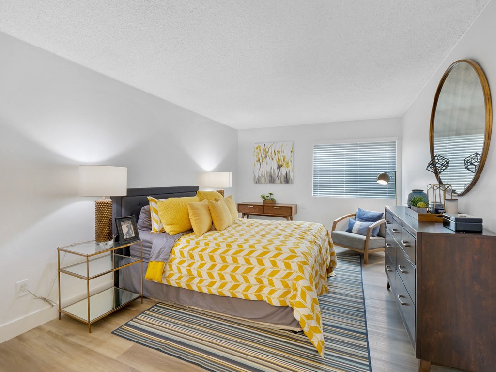 A bedroom with a bed, nightstand, and chair at Verandas Apartments, West Covina, CA, 91791