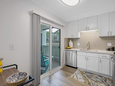 A kitchen with white cabinets and a marble floor.
