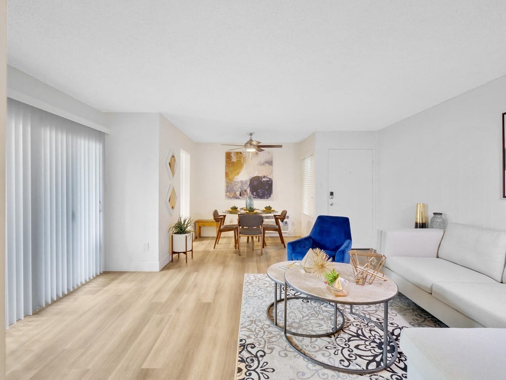 A living room with a white couch, a coffee table, and a dining table with chairs at Verandas Apartments, California, 91791