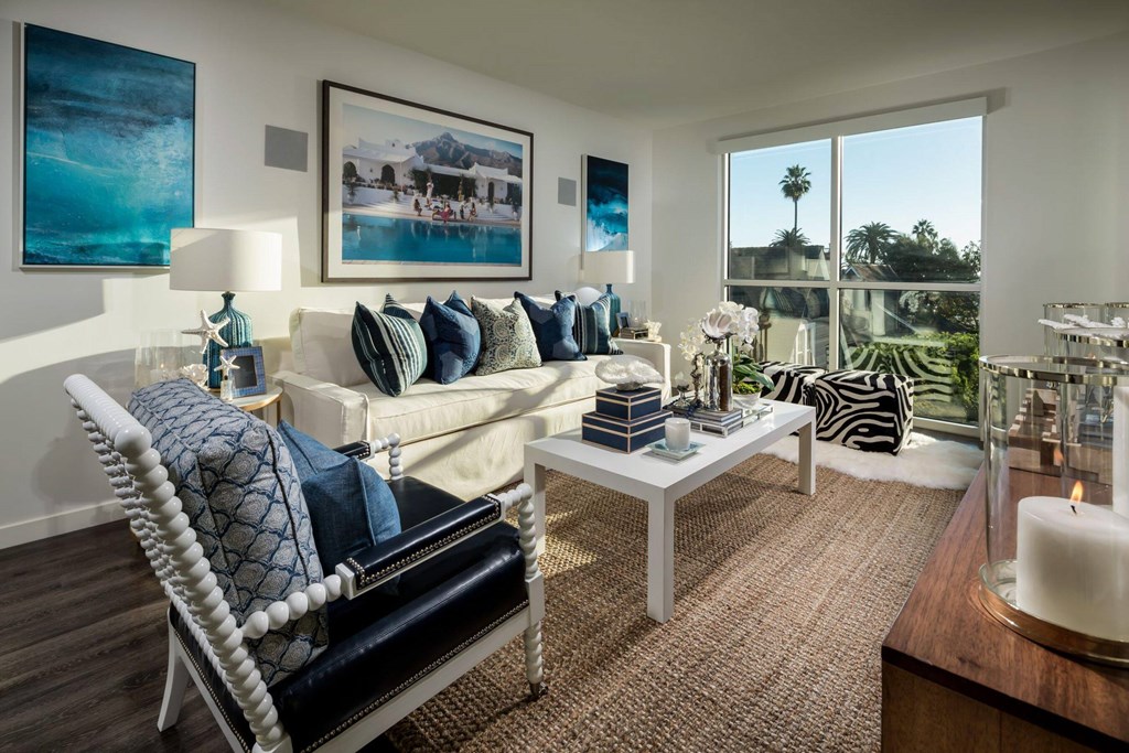 A living room with a white sofa and a large window.at Chelsea Santa Monica, Santa Monica, CA  