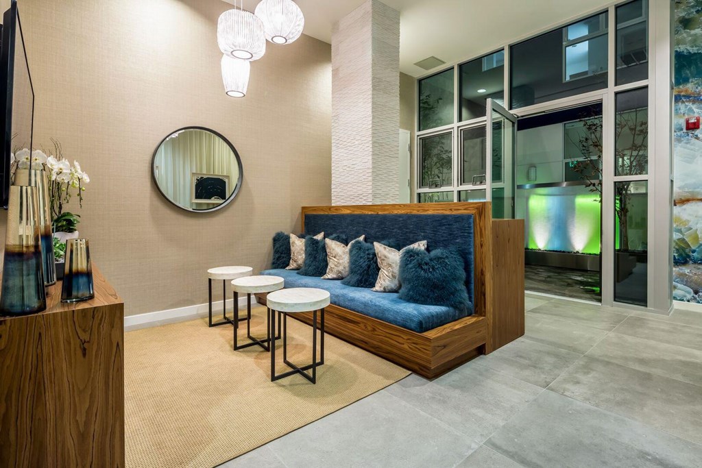 A modern living room with a blue couch and a round mirror on the wall.at Chelsea Santa Monica, Santa Monica  