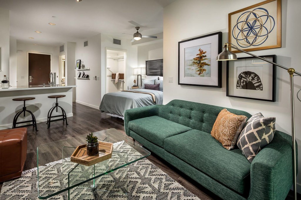 A living room with a green couch and a glass coffee table.at Chelsea Santa Monica, Santa Monica, CA 90411  