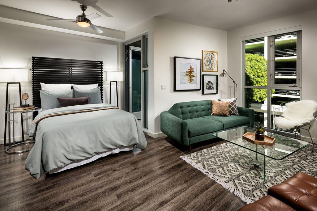 A bedroom with a bed, a green couch, and a glass table.at Chelsea Santa Monica, Santa Monica, CA  