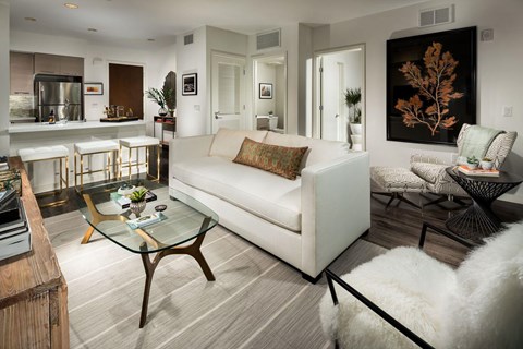 A modern living room with a white couch and a glass coffee table.