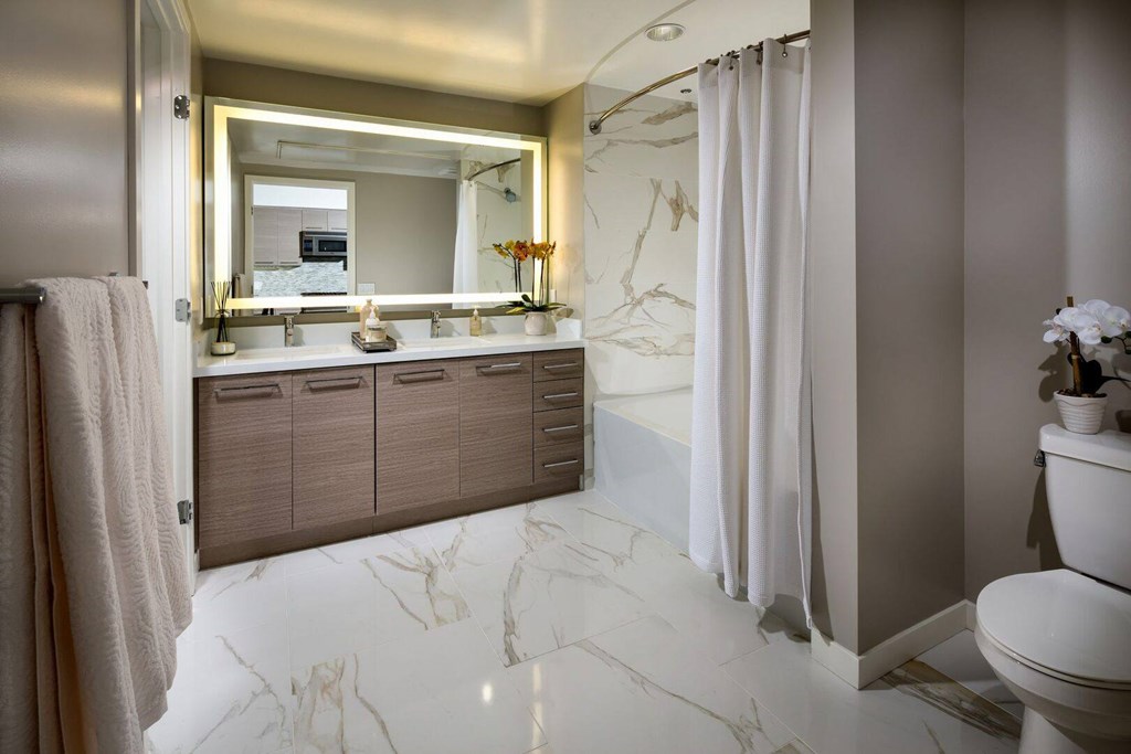 A bathroom with a marble floor and a large mirror above the sink.at Chelsea Santa Monica, Santa Monica California  