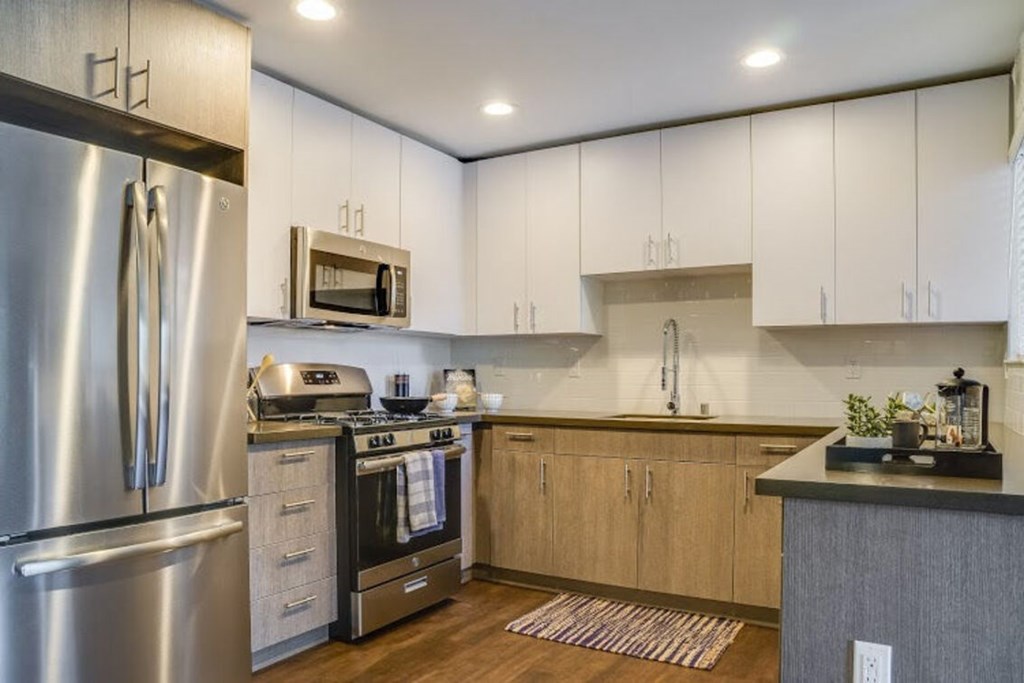 A modern kitchen with a stainless steel refrigerator and wooden cabinets.at Solterra At Civic Center, California, 90650-8308