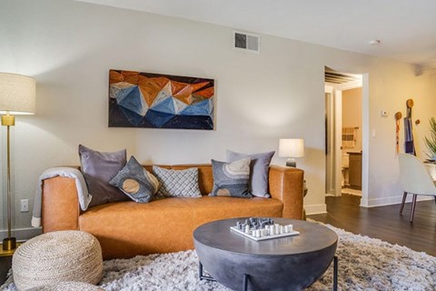 A living room with a couch, a table, and a painting on the wall.