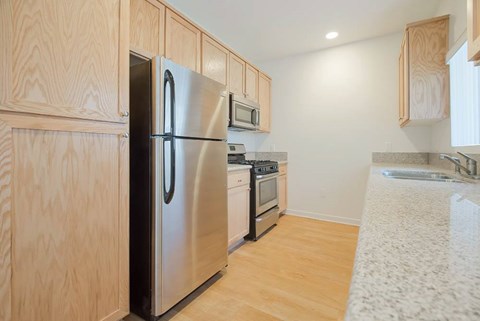A kitchen with a stainless steel refrigerator and wooden cabinets.