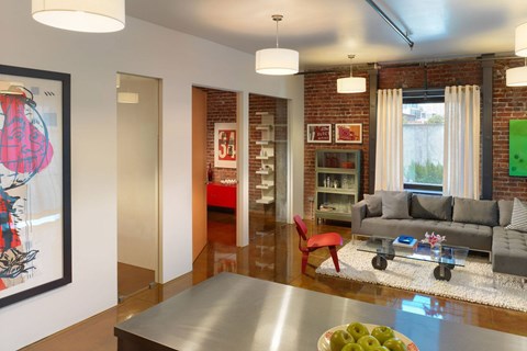 A modern living room with a grey couch and a red chair.