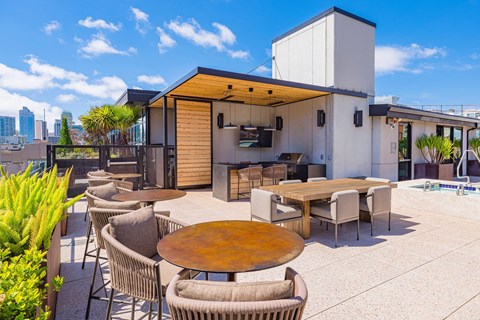 A modern outdoor dining area with a wooden table surrounded by chairs.