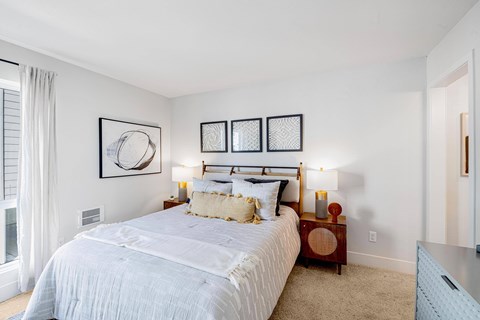 A bedroom with a large bed and a window with curtains.
