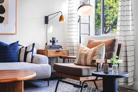 A living room with a grey couch, a brown chair, and a wooden table.