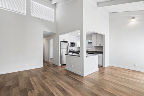 A kitchen with white cabinets and a wooden floor.