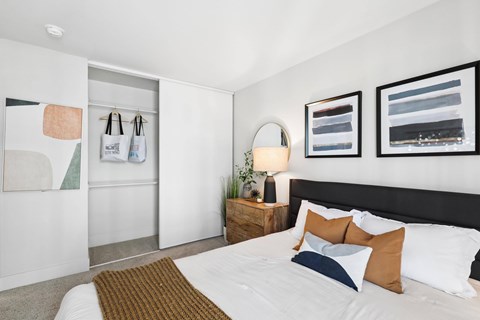 A bedroom with a bed, nightstand, and two wall hangings.