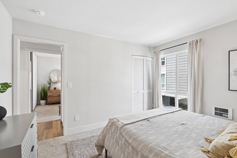 A bedroom with a large bed and a window with blinds.