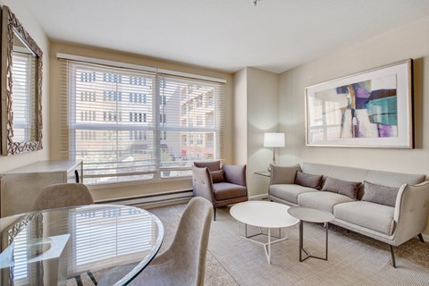 San Rafael, CA, Apartments Near Mount Tamalpais State Park - Rafael Town Center - Cozy Living Room with Sofa, Accent Chair, Round Coffee Tables, Soft Carpet, and Open Kitchen Breakfast Bar.