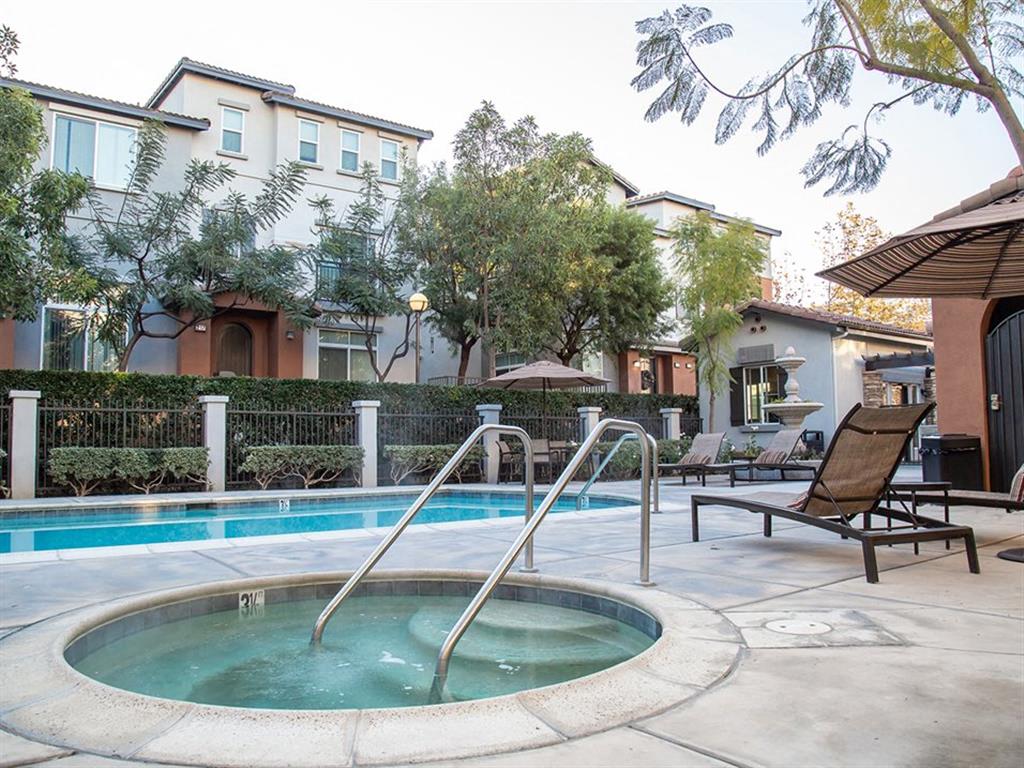 Pet-Friendly Apartments in Tustin, CA - Tustin Cottages - Pool with a Jacuzzi, Trees, and Brown Lounge Chairs