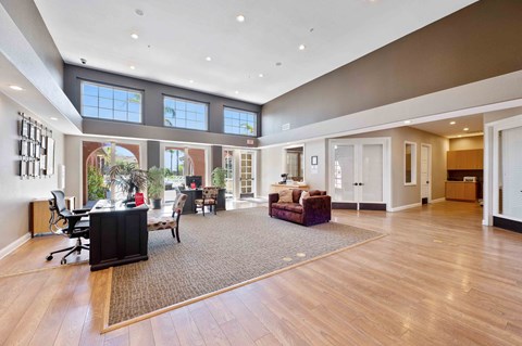A spacious living room with a large window and a wooden floor.