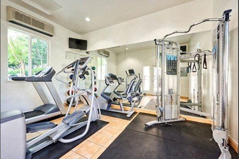 Tustin, CA, Townhomes With Attached Garage - Tustin Cottages - Fitness Center With Treadmill, Cardio Equipment, Elliptical, Stationary Bike, Mirrors, Mounted Monitor, and Strength-Training Equipment.