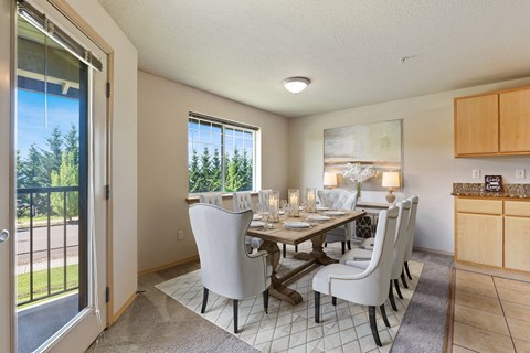 A dining room with a table set for two and a view of the backyard.