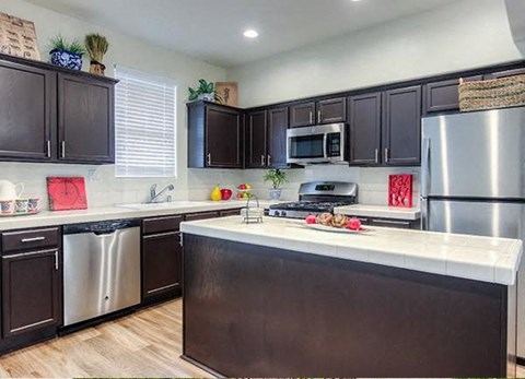 Tustin, CA Apartments for Rent - Tustin Cottages - Kitchen with an Island, Brown Cabinets, and Stainless-Steel Appliances