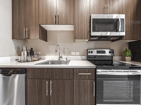 Dog-Friendly Apartments in North Seattle, WA - Origin - Kitchen with Flat-Panel Wood Cabinets, Stone Countertops, and Stainless Steel Appliances.