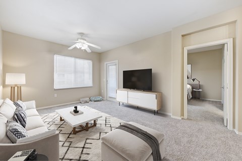 2-Bedroom Apartments in Upland, CA - Park Central Apartments - Living Area with Carpet Flooring, Couch, Ottoman, Coffee Table, Side Table, Floor Lamp, Ceiling Fan, Media Console, and Television.