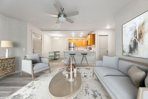 Vancouver, WA, Apartments Near Prairie High School - Prairie Home Apartments - Open Living Room With Couch, Armchair, Ceiling Fan, Oval Coffee Table, Console Cabinet, Lamp, and Large Wall Art.