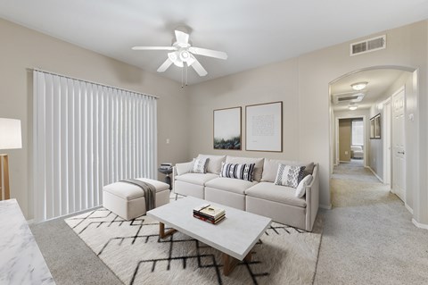 A living room with a white couch, a coffee table, and a ceiling fan.
