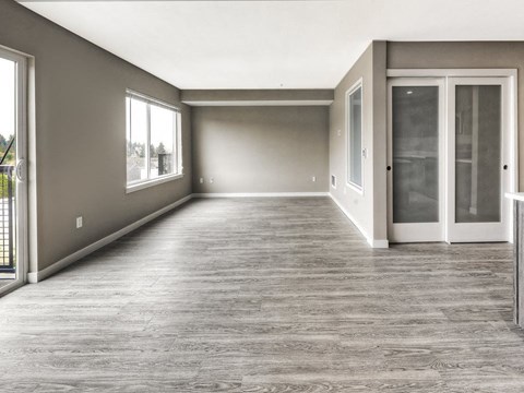North Seattle, WA, Pet-Friendly Apartments - Origin - Living Area with Wood-Style Flooring, Large Windows, and Sliding Glass Doors to Balcony.