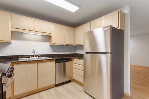 A kitchen with a stainless steel refrigerator and wooden cabinets.
