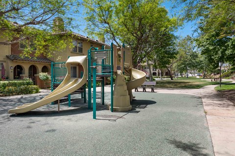 A playground with a yellow slide and a green railing.