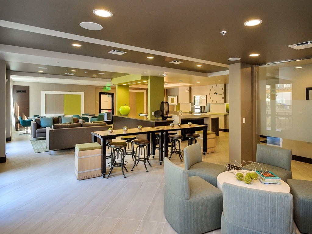 a large lobby with tables and chairs and a kitchen