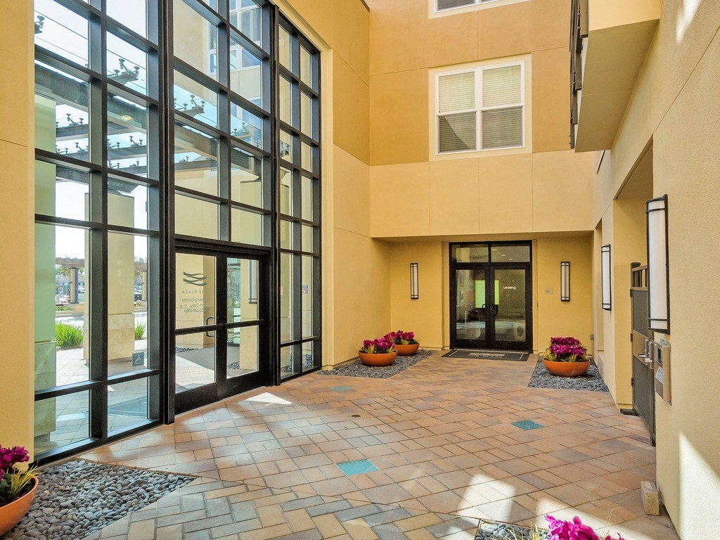 a lobby of a building with large windows and a brick floor