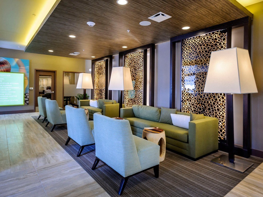 a lobby of a hotel with couches chairs and lamps