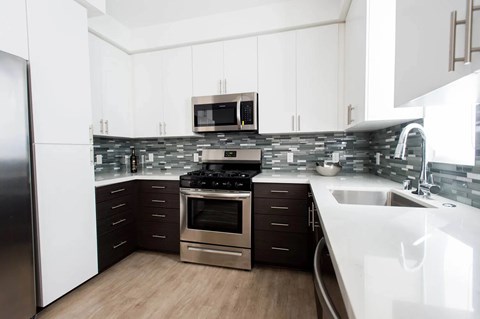 A modern kitchen with a stainless steel refrigerator and a white countertop.