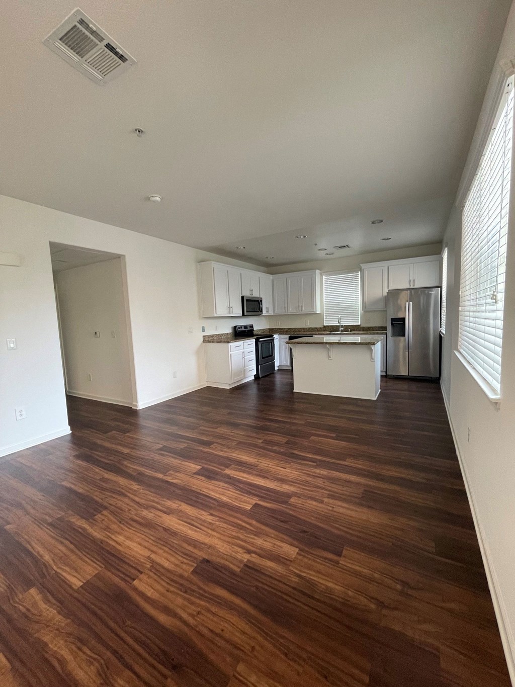 an empty living room and kitchen with wood flooring