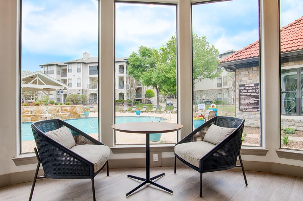 a patio with two chairs and a table in front of a large window