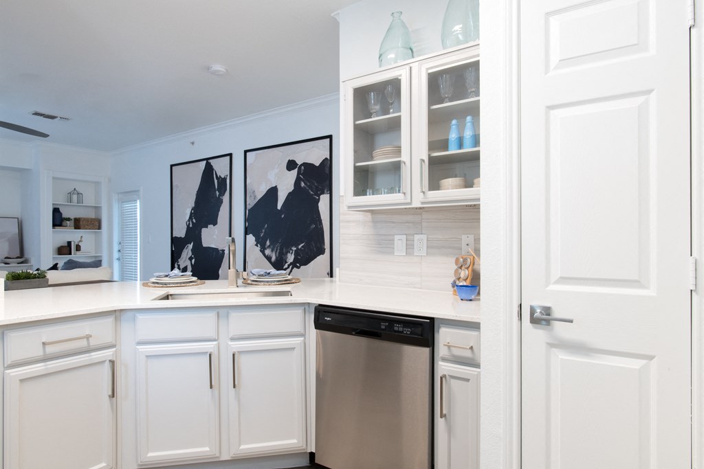 a kitchen with white cabinets and a stainless steel dishwasher