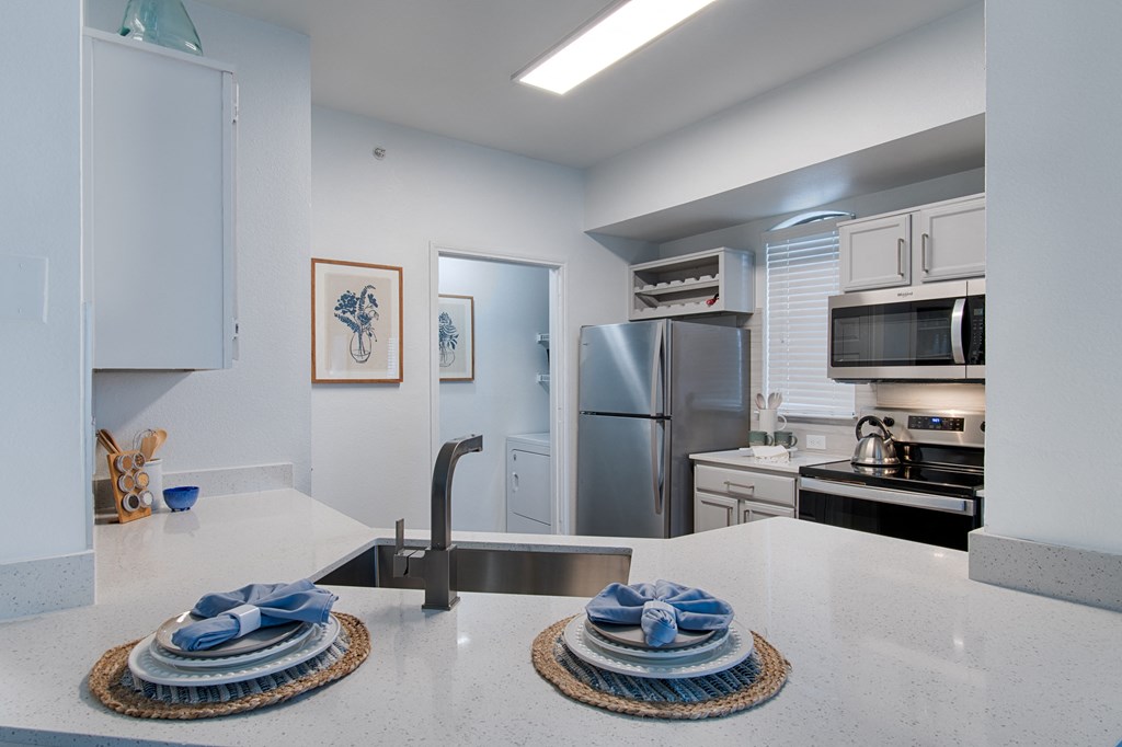 a kitchen with white countertops and stainless steel appliances