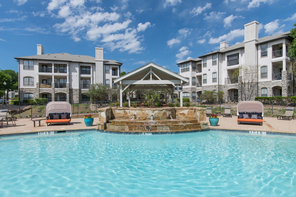 a large swimming pool with a waterfall in front of an apartment complex