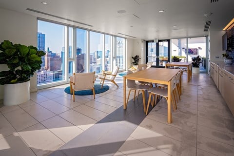 A modern kitchen with a dining table and chairs in front of a large window overlooking a cityscape.