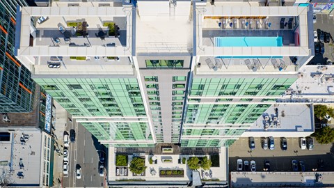 A modern building with a glass facade and a pool on the top floor.