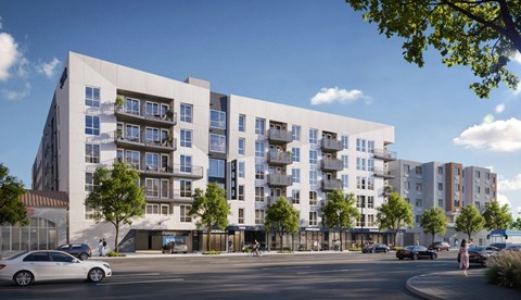 A modern apartment complex with cars parked in front.
