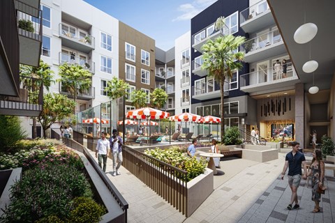 A street view of a residential area with people walking and a row of plants on the left.