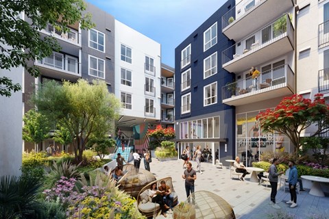 A modern apartment complex with a courtyard garden and people socializing.